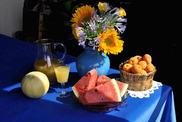 Stillleben auf dem Tisch ein Blumenstrauß in einer Vase, eine Wassermelone, eine Melone und ein Krug mit Saft