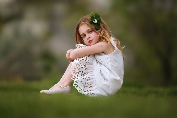 Fille dans une robe blanche avec une épingle à cheveux sur l herbe