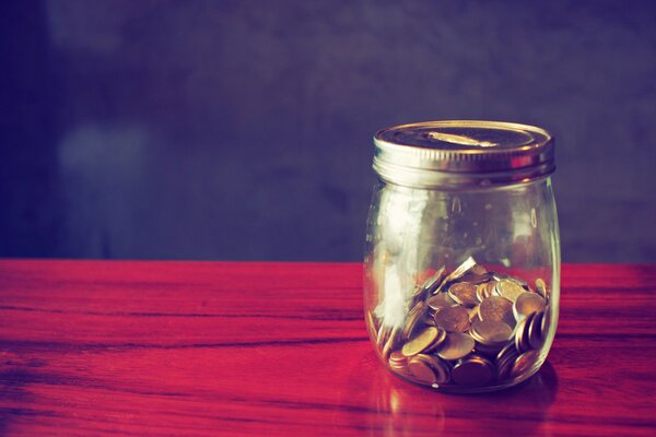 Money piggy bank with coins on the red table