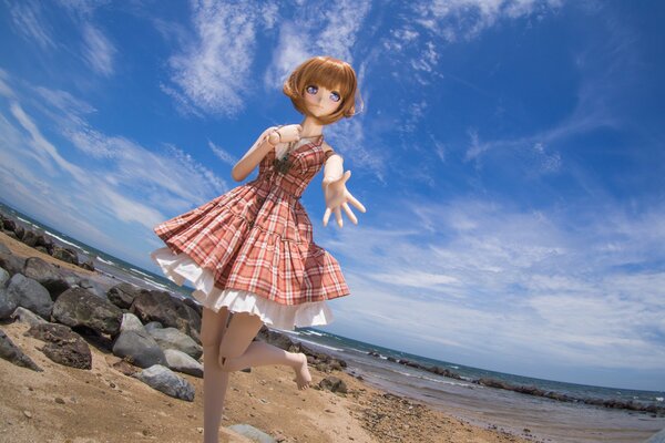 Puppe Spielzeug im Kleid am Strand in der Nähe des Meeres