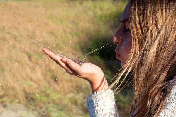 Ein Hauch eines Mädchens auf der Handfläche von einem Sandkorn