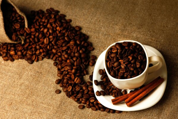 Imagen de granos de café con una taza y canela sobre un fondo marrón