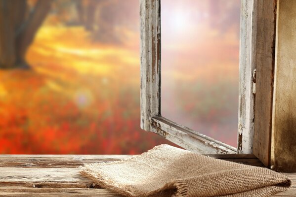 Burlap on the window with a view of the autumn landscape