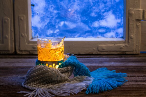 A cup of hot tea in front of a frozen window