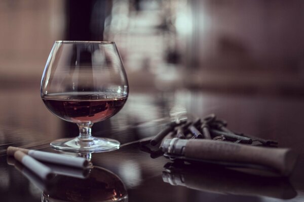A glass of cognac on the table with cigars