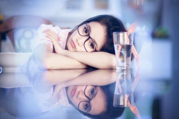 Jeune fille dans des verres sur fond bleu et un verre d eau