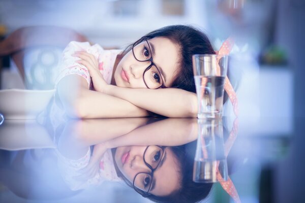 Ragazza con gli occhiali su sfondo blu e un bicchiere d acqua