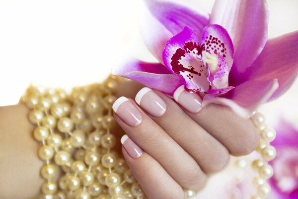 A woman s hand with a manicure holds a flower