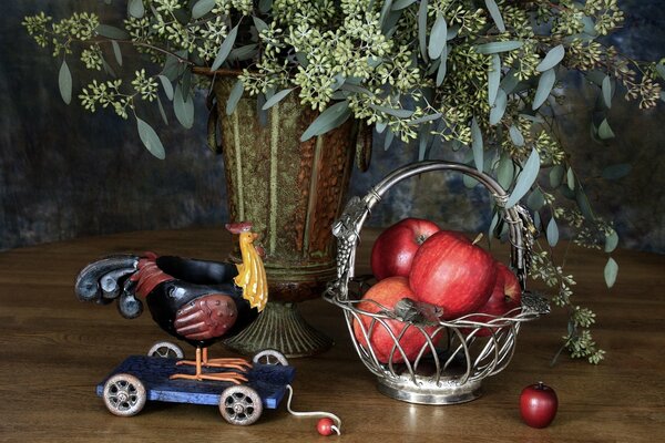 Nature morte représentant des pommes rouges dans un panier, un coq et un vase