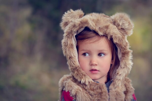 A little girl in a tank top with ears on the hood