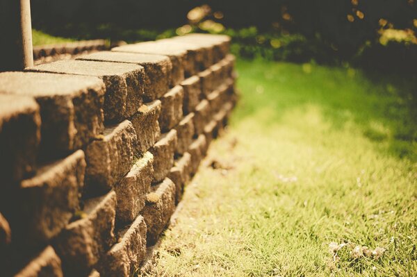 Pared de piedra sobre fondo de hierba verde