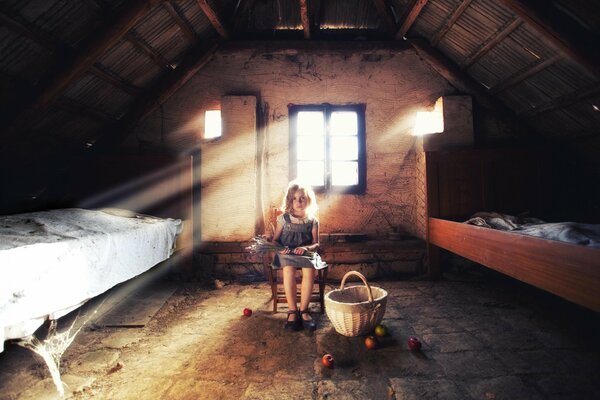 The girl is sitting in the attic with a basket