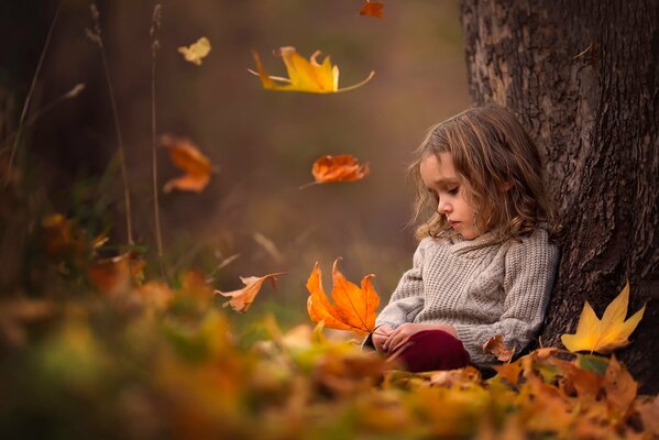 A girl under a tree with leaves in her hands