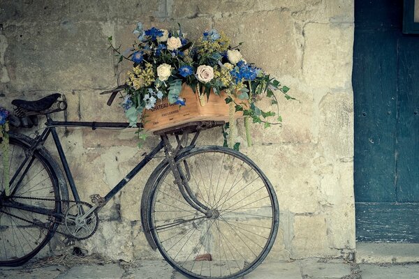 Vélo avec des fleurs debout près du mur
