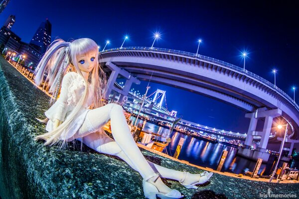 Muñeca de juguete en el puente del paseo marítimo en la ciudad nocturna
