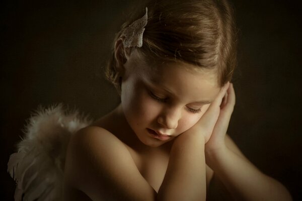 Маленькая светловолосая девочка в костюме ангела