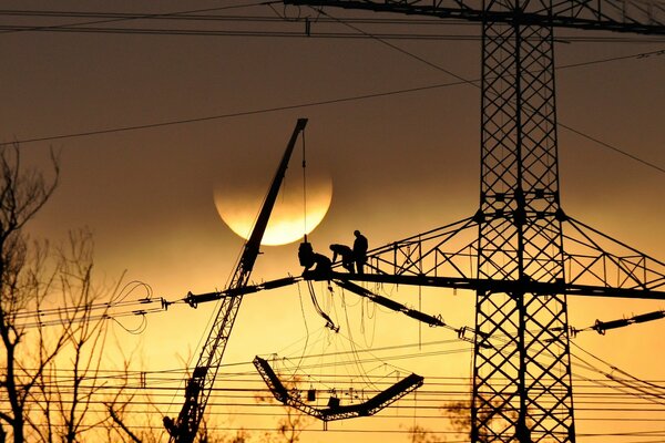 Photo les électriciens travaillent en altitude au coucher du soleil