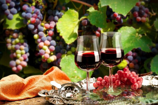 A tray with grapes and glasses of red wine