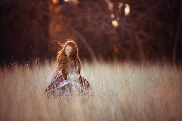Red-haired girl in the wind in the field