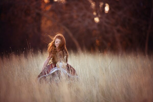 Pelirroja chica en el viento en el campo