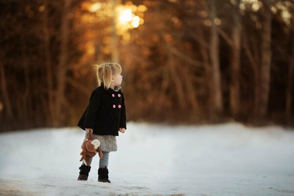 Ragazza con il giocattolo sulla strada innevata