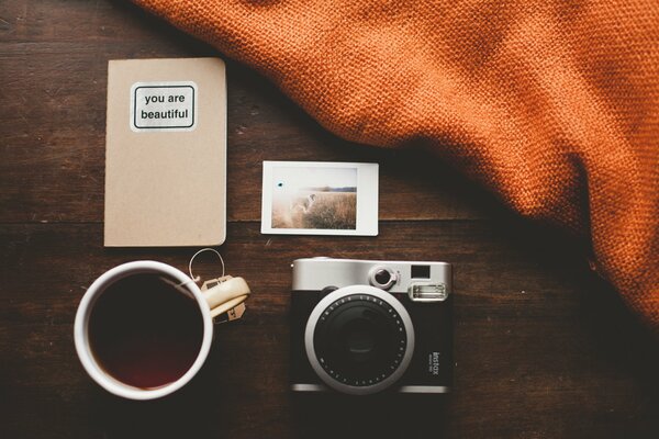 A camera with a mug of tea next to a blanket