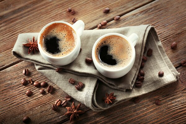 2 cups of coffee on a napkin around coffee beans