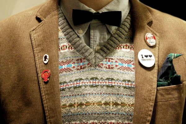 A brown corduroy jacket with a badge and . A black butterfly. Multicolored vest