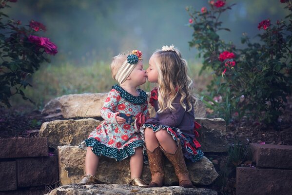 Chicas lindas besándose en el fondo de piedras y flores