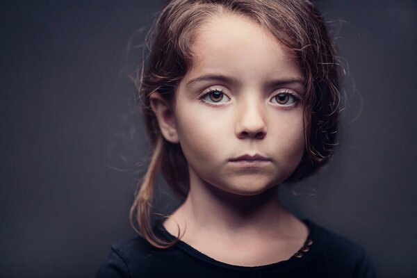 Retrato de una niña de ojos marrones sobre un fondo oscuro