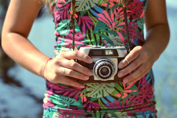 Старый фотоаппарат с ремешком в руках девушки