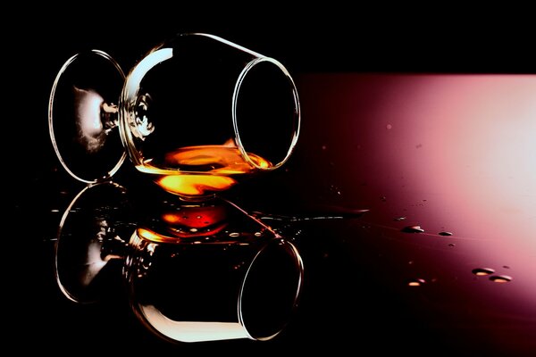 Drops of cognac on the glass of a glass and alcohol as a background