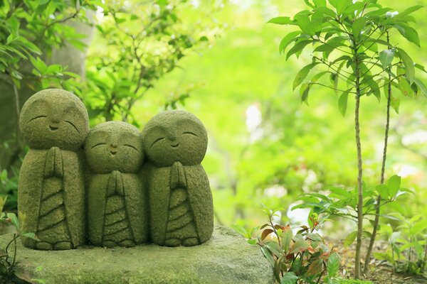 Японские статуэтки дзидзо на фоне леса