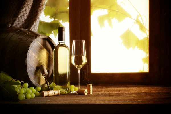 En el alféizar de la ventana hay un vino, una Copa, uvas y un barril