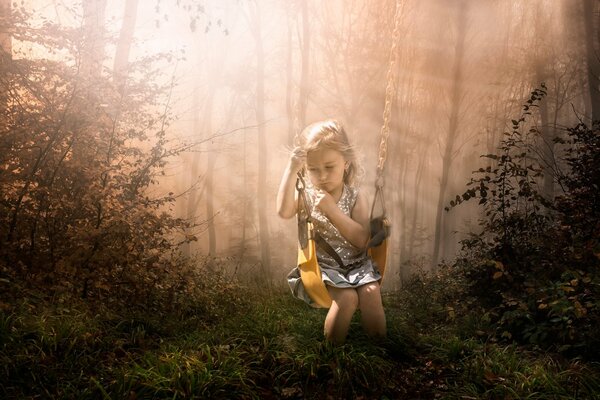 Little girl on a swing in the woods