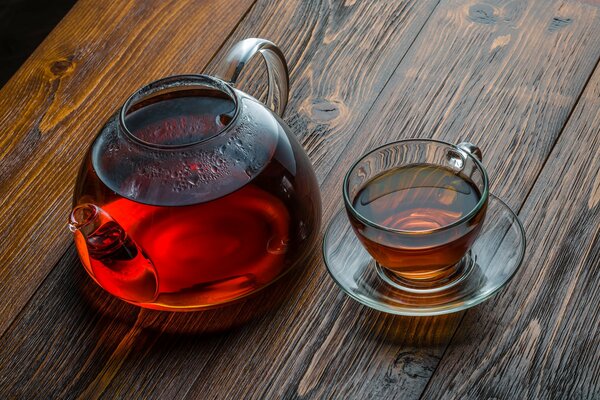 Théière en verre avec une tasse de thé sur la table