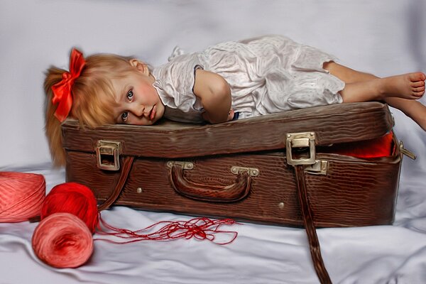 Petite fille avec un arc rouge se trouve sur une valise