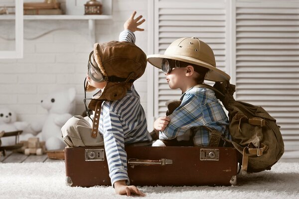 Chłopcy bawią się w lotników siedząc w walizce