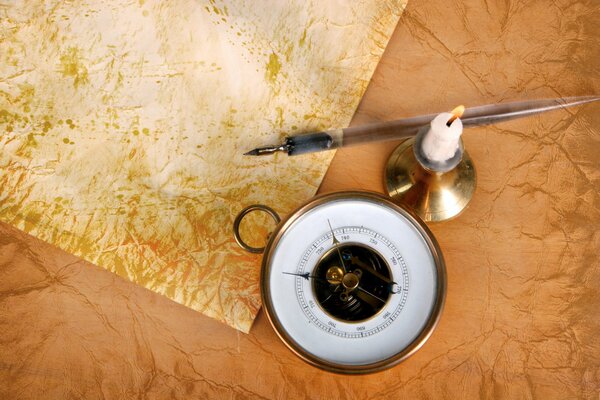 Compass, candle holder with burning candle and paper with pen