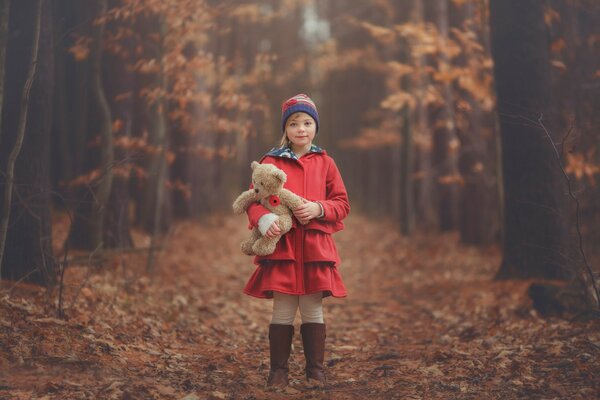 Mädchen im Herbst im Wald mit Teddybären-Spielzeug