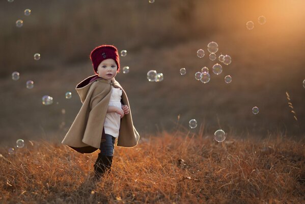 A boy in a field among soap bubbles