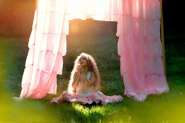 Photo of a little girl dreaming on a green lawn