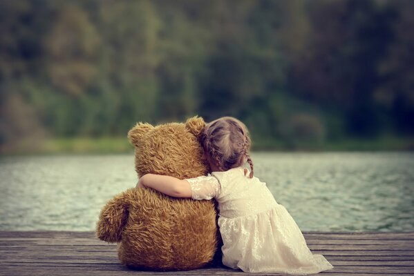 Una niña en el fondo del lago abraza a un oso