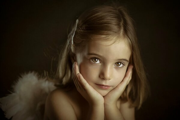 Petit ange fille avec les mains sur le menton