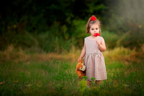 A girl with a toy and a poppy in a clearing