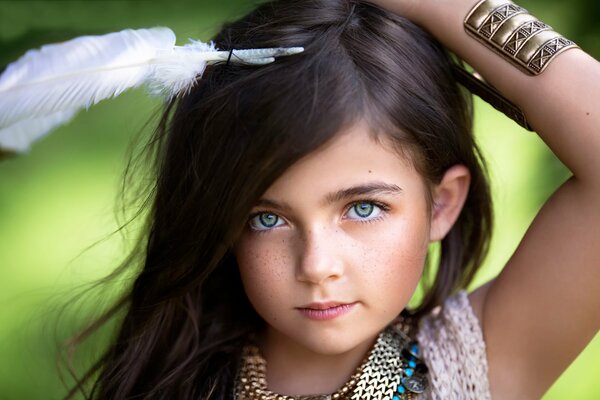 A little girl with green eyes and dark hair with a feather