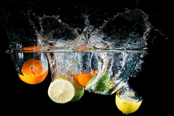 Citrus fruits in splashes of water on a black background
