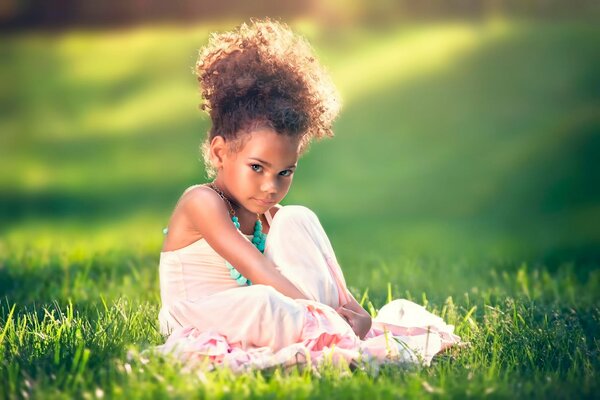 Kręcone dziewczyna siedzi na trawie