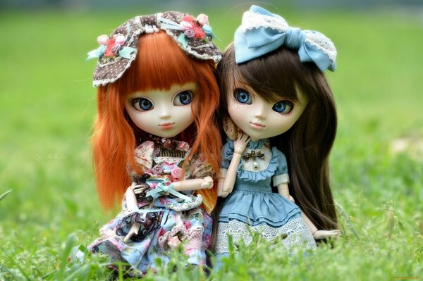 Two doll toys with bows on the grass