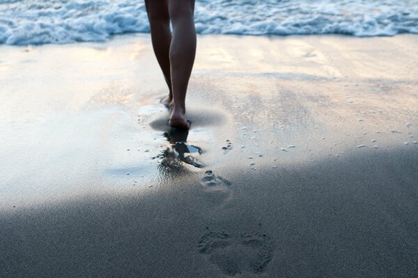 Eine Frau geht zum Meer und hinterlässt Spuren im Sand